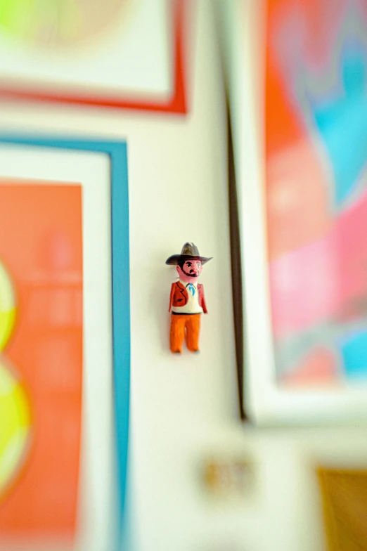 a tiny figurine with an orange shirt and cowboy hat