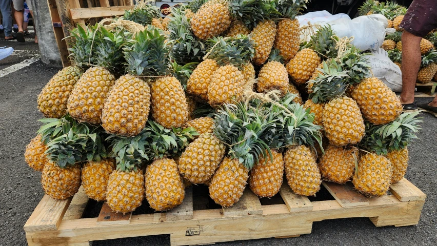 pineapples are piled on wooden crates at a fruit market