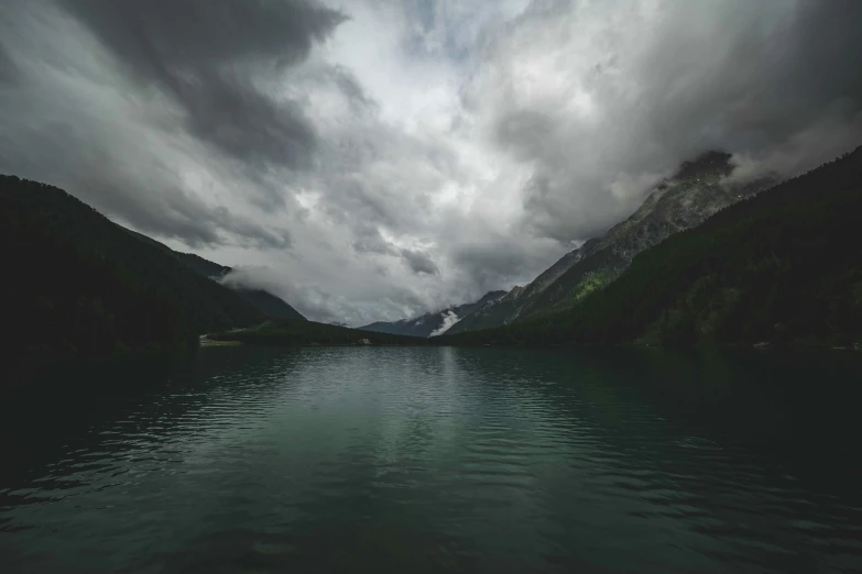 mountains rise over the water and cover with clouds