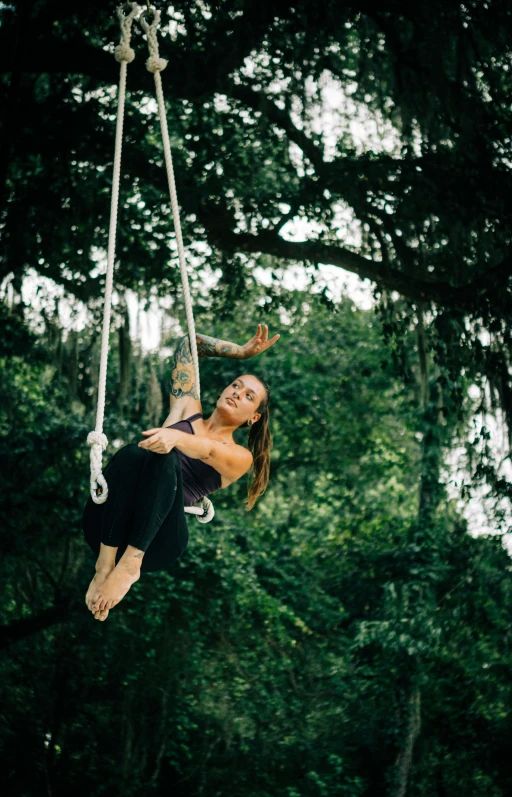 a woman hanging from the side of a tree swing