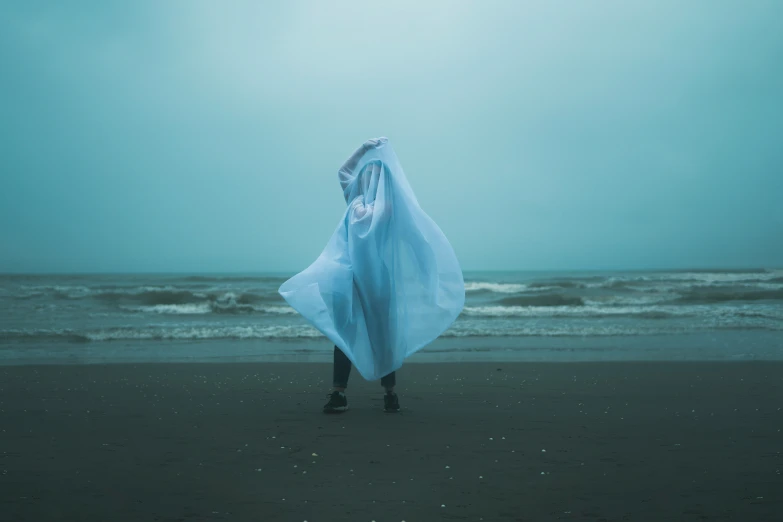 the person is walking on a beach holding a blue sheet