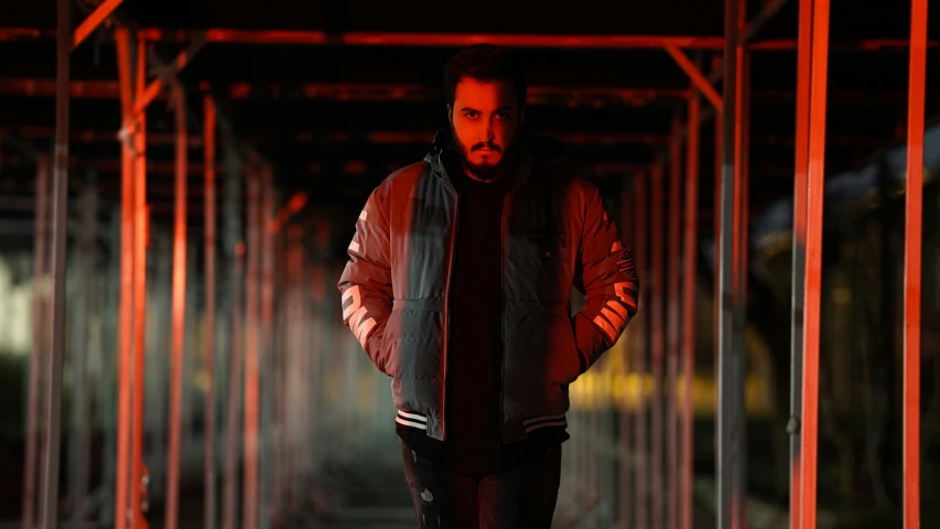 a man with a beard standing in a tunnel of red lights