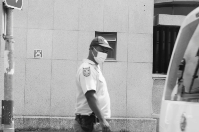 police man walking past a white van wearing a face mask