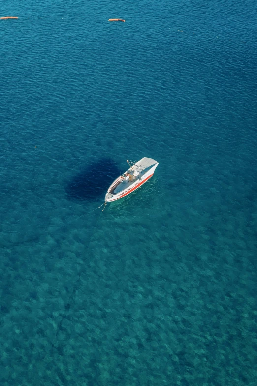 boat floating in clear blue ocean water with wake