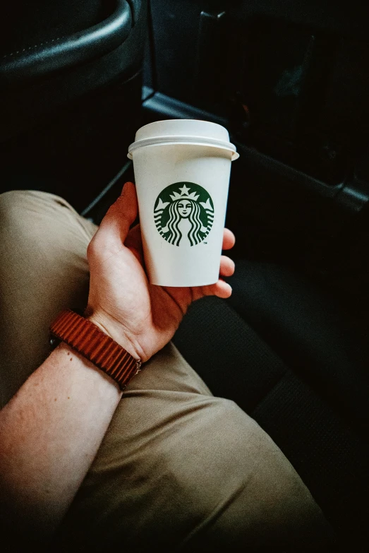 a woman is holding up a starbucks cup