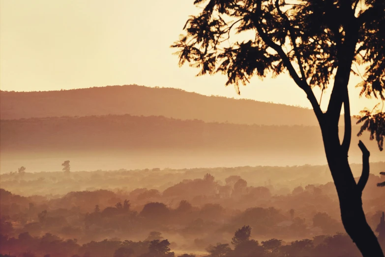 this is the sun setting over some hills and trees