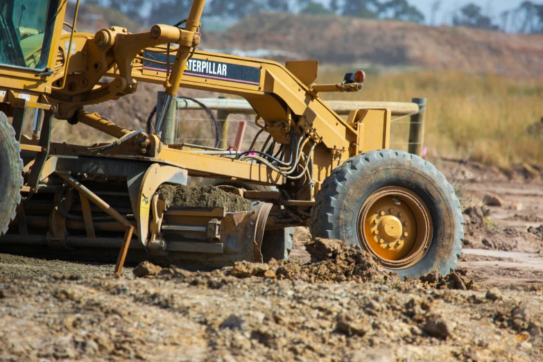 a large yellow bulldozer digging through a field