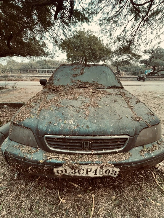 a dirty car that is sitting on some leaves