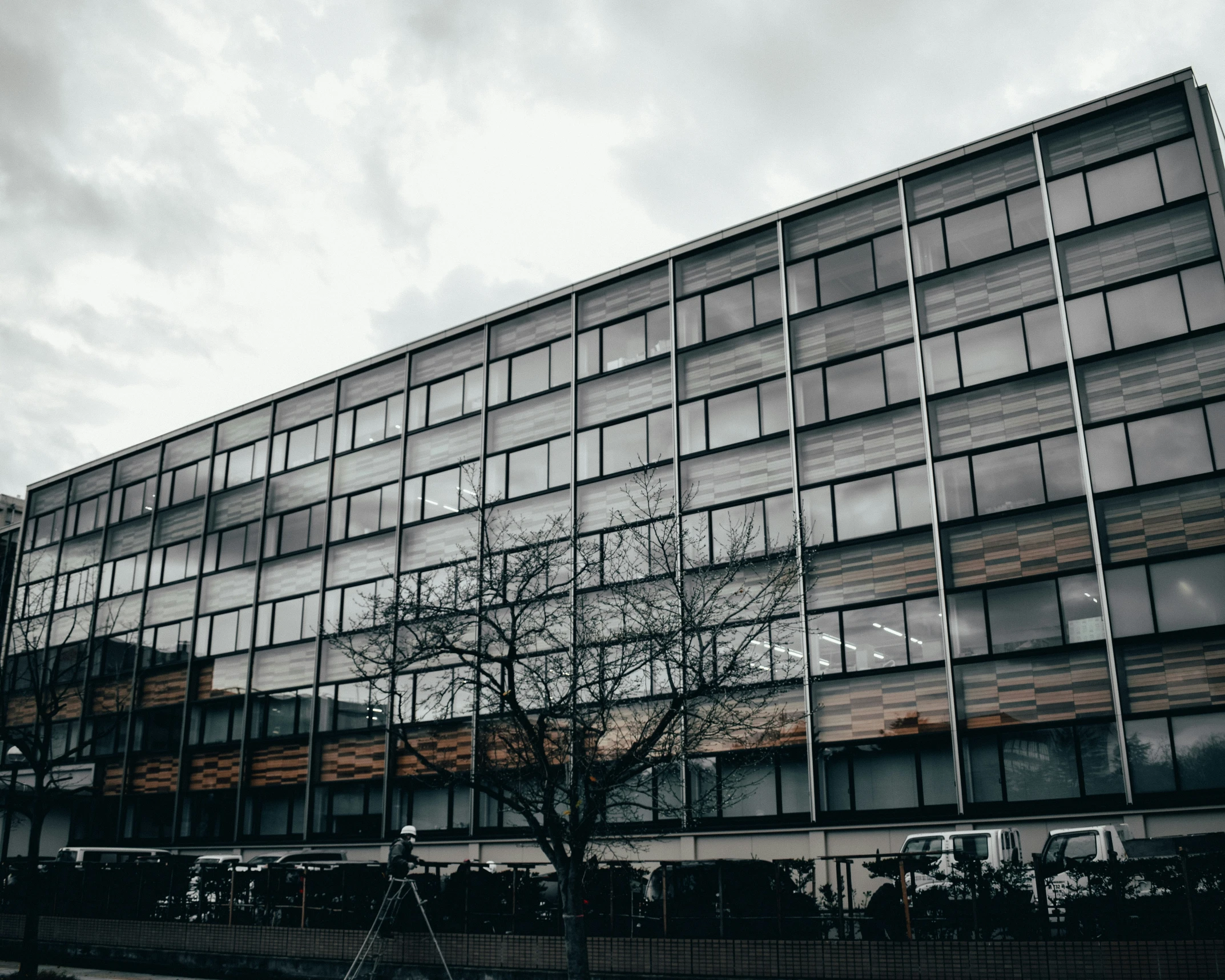 an office building with trees and cars parked in front