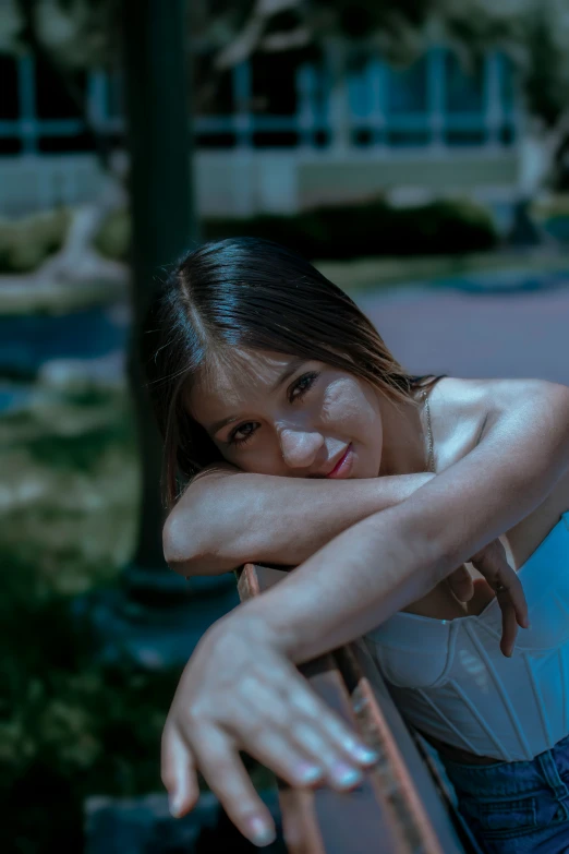 a beautiful young woman leaning against a bench outdoors