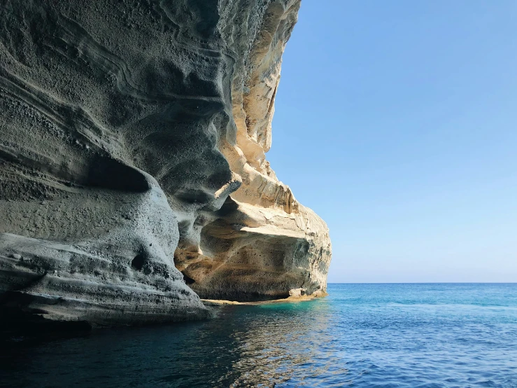 an interesting cliff in the middle of blue water