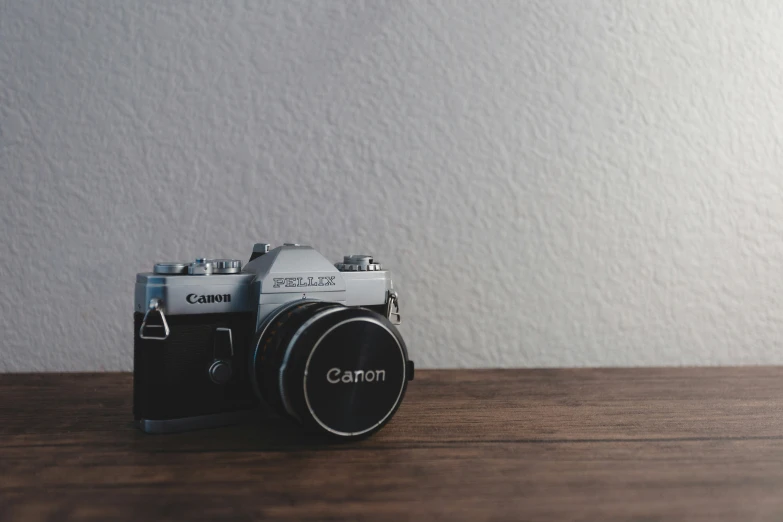 a digital camera on a wooden table with a wall behind it