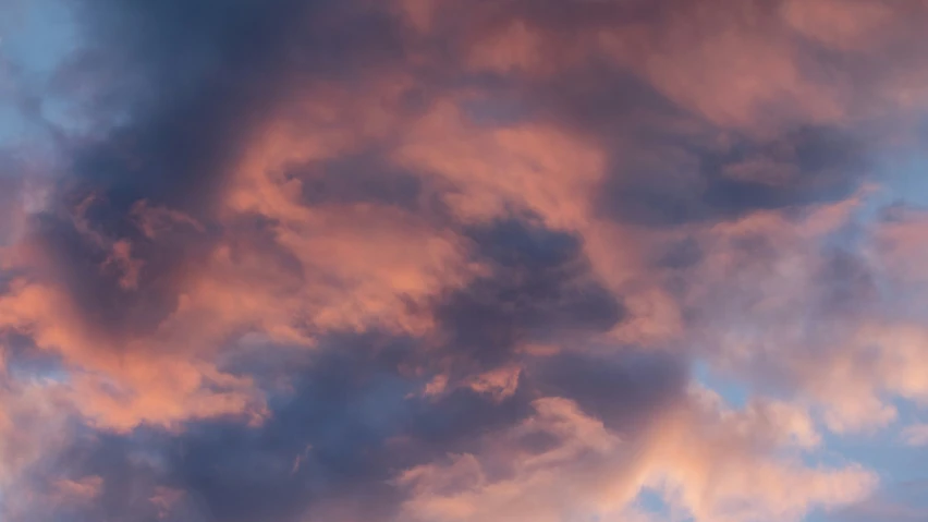 a cloudy sky is pictured with an airplane flying high