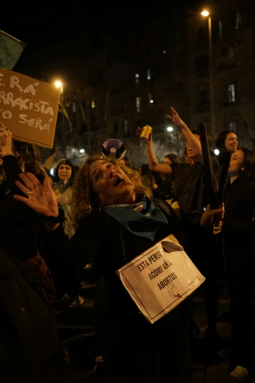 a woman in the middle of a rally holding up signs