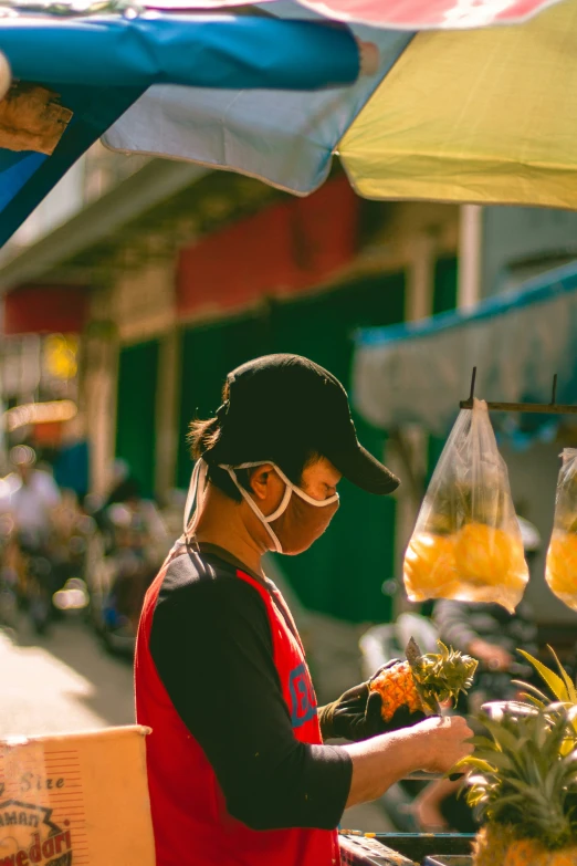 a person with glasses and a red shirt standing in front of a table filled with produce