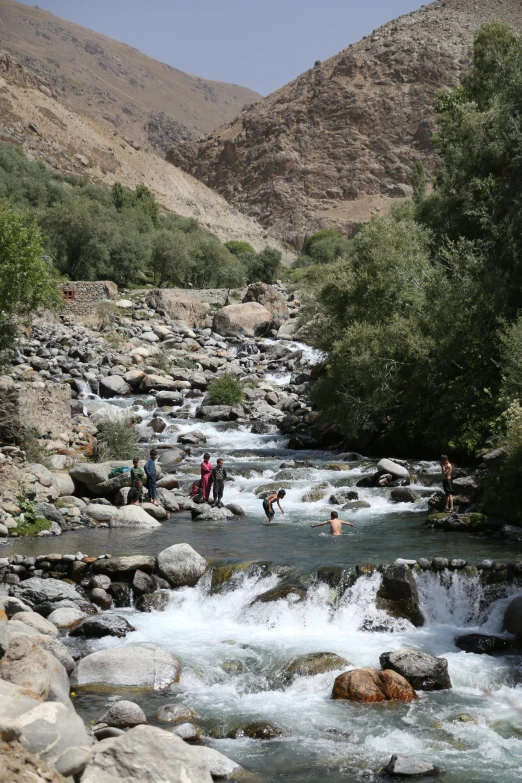 people are walking over rocks next to a river