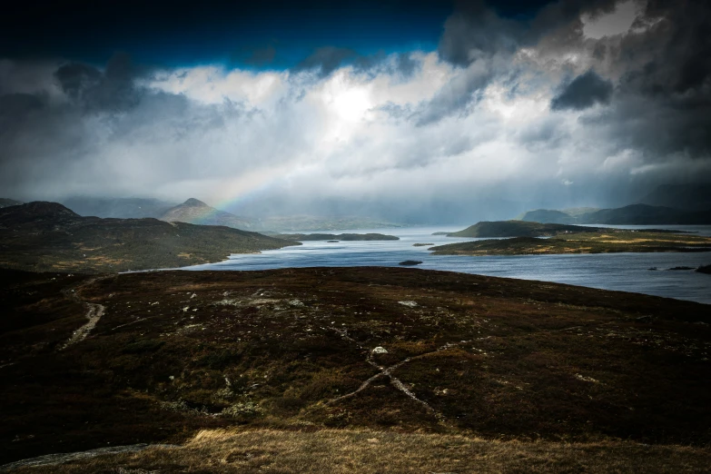 a very cloudy sky with a rainbow in the distance