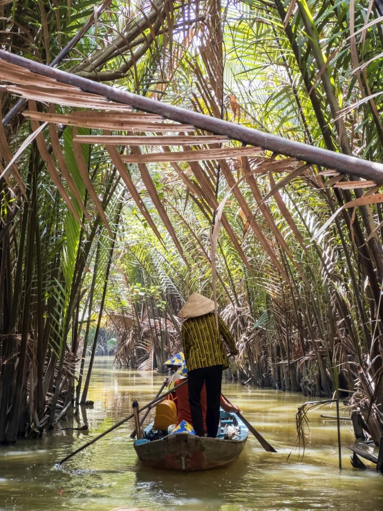 a woman rowing down a stream on a small boat