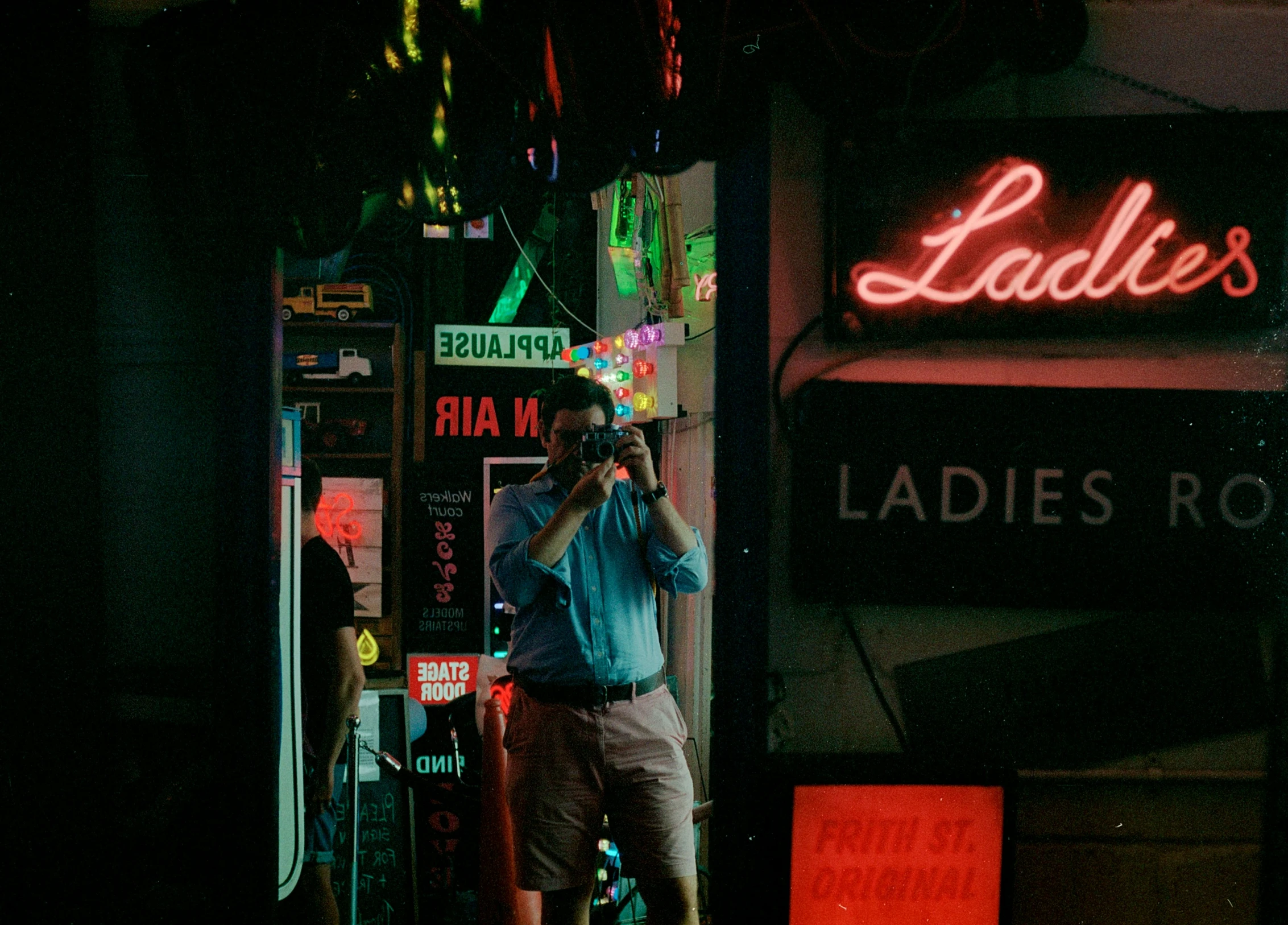 man talking on cell phone in city with neon lights and business signs