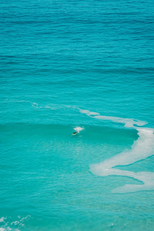 the view from a hill top looking at a surfer riding the waves