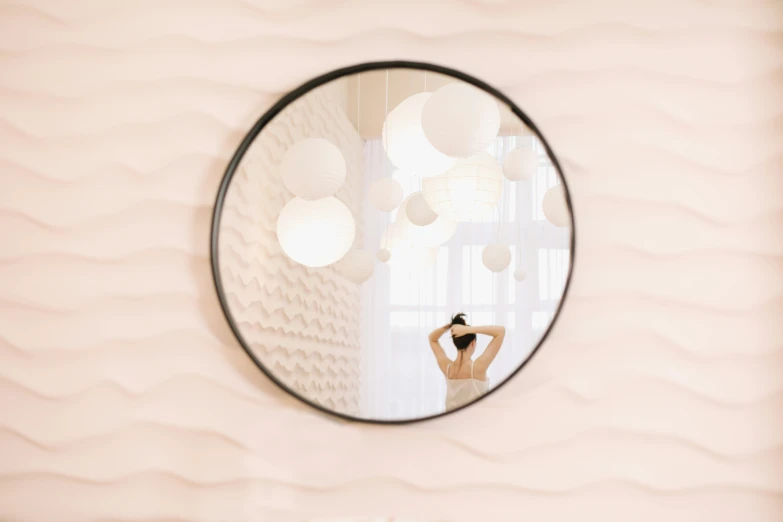 a reflection of a woman standing in front of a circular mirror