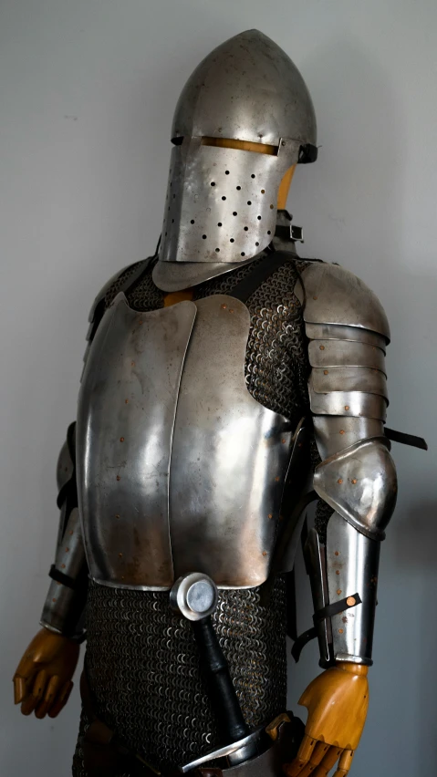 a man wearing armor stands next to a sword