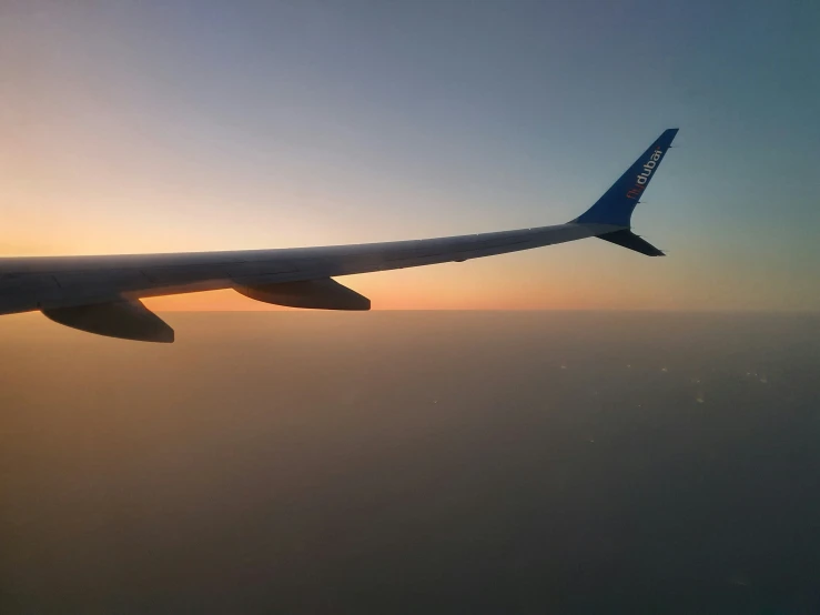 the wing of an airplane that is flying in the sky