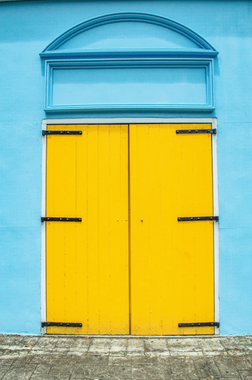 a po of a yellow door that is in the middle of a blue building