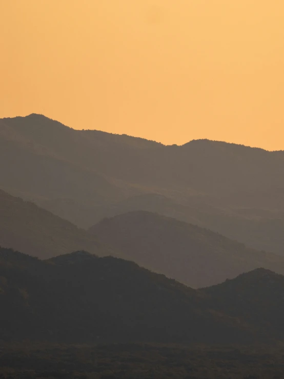 the sun is setting over a hill covered in mountains