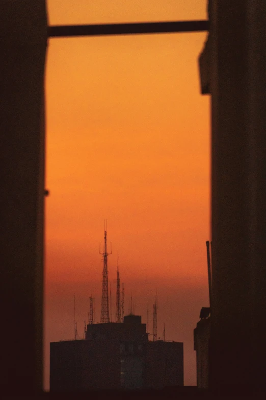 the setting sun in a dark city with building in silhouette