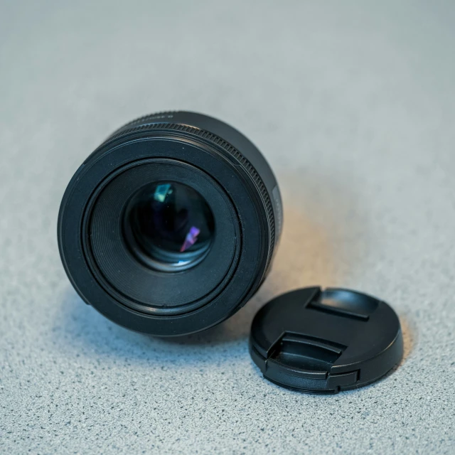 a black camera lens sitting on a table next to an open lid