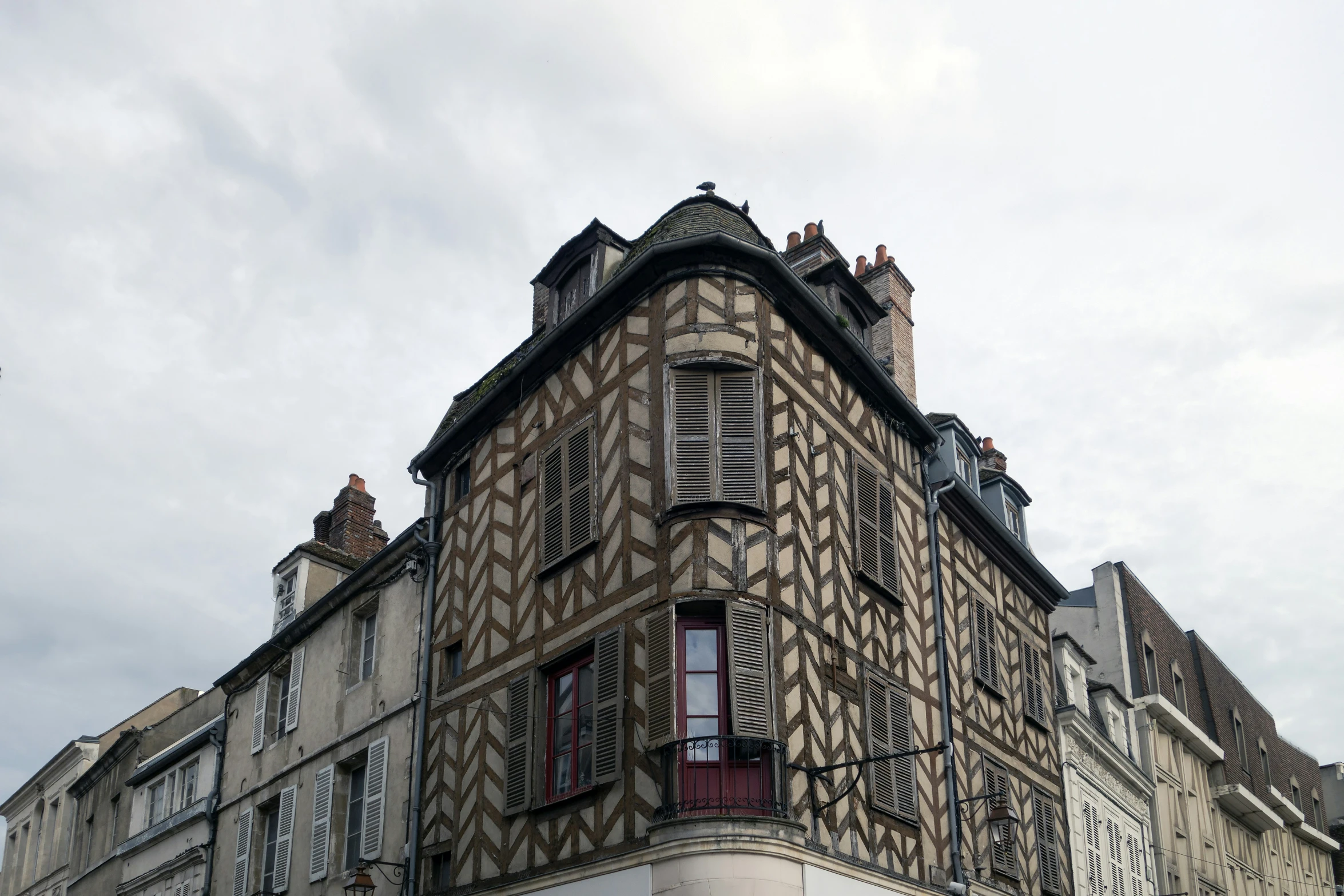 a tall building with windows and shutters in the roof