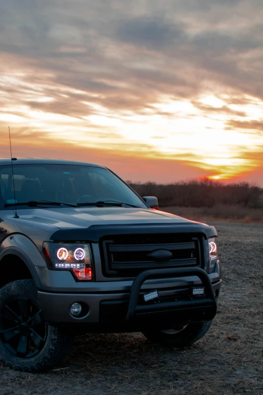 the truck is parked in the dirt and sunset