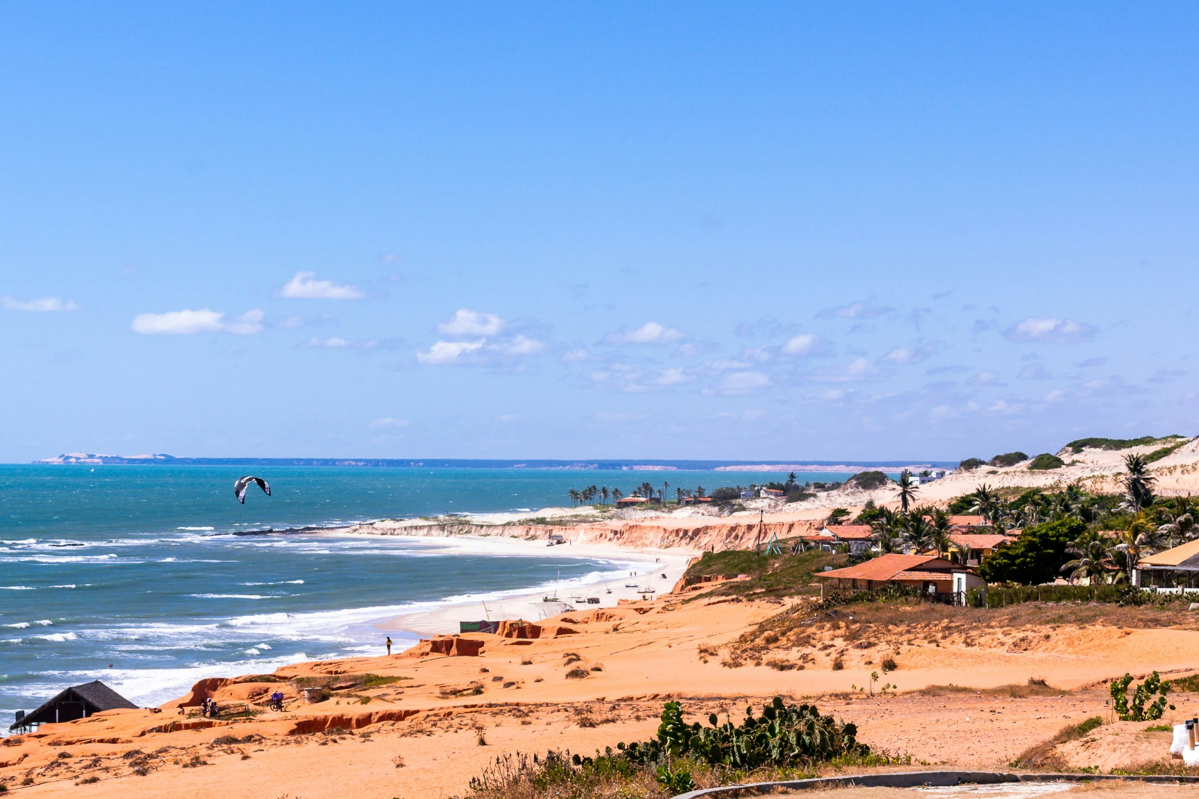 the beach is lined with houses, surfboards and parasailing