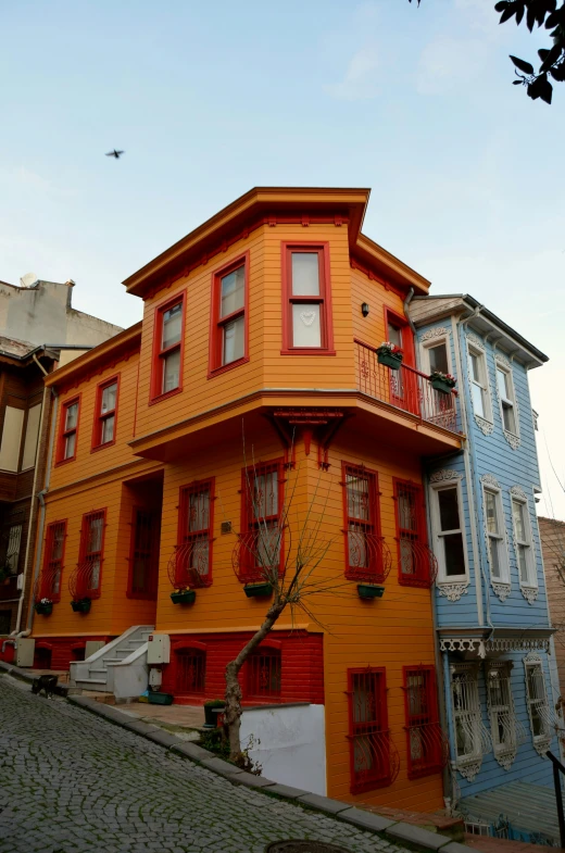 an orange and blue building next to buildings with flowers on the windows