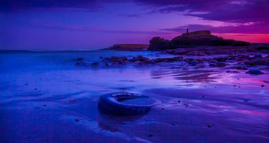 a tire lying on a wet beach at sunset