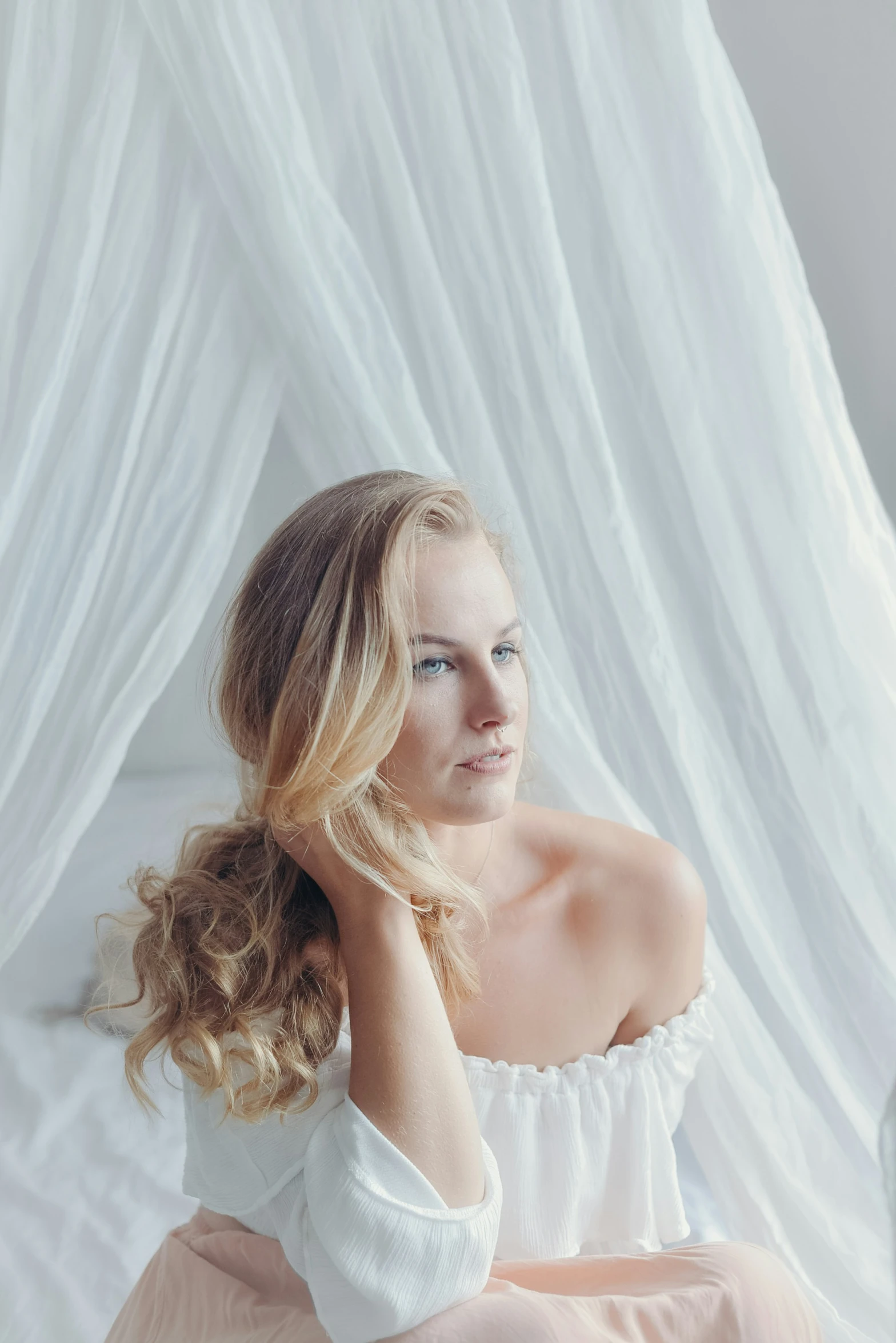 a young woman sits wearing a white shirt