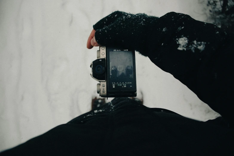 a person standing in the snow holding up a cell phone