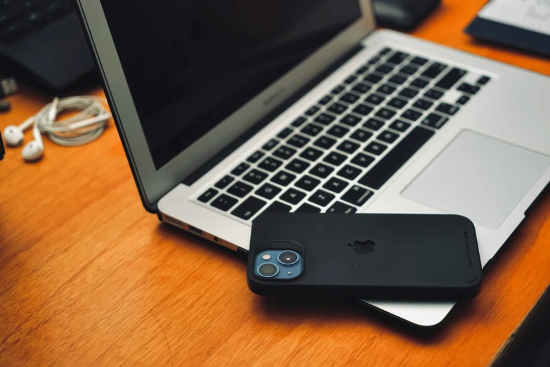 a cellphone and laptop on a wooden desk