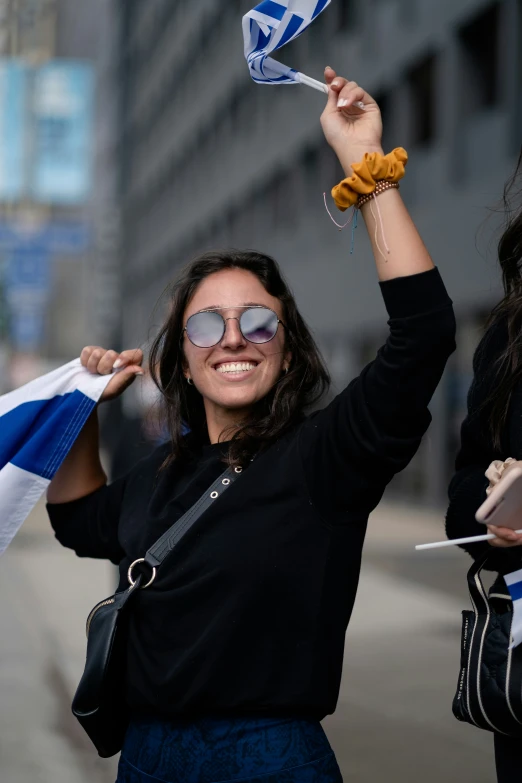 a woman holding up a flag and another person holding a cellphone