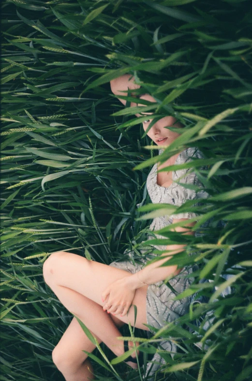 a girl sitting alone in tall grass, on the ground