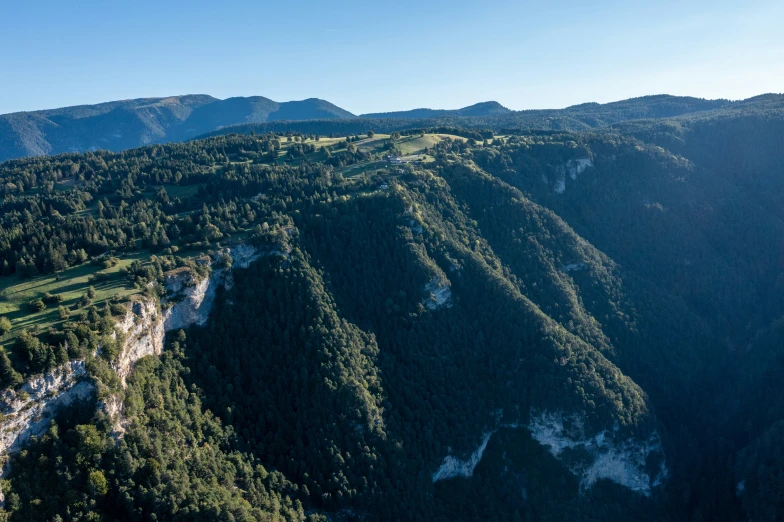 a mountain with tall green trees surrounded by mountains