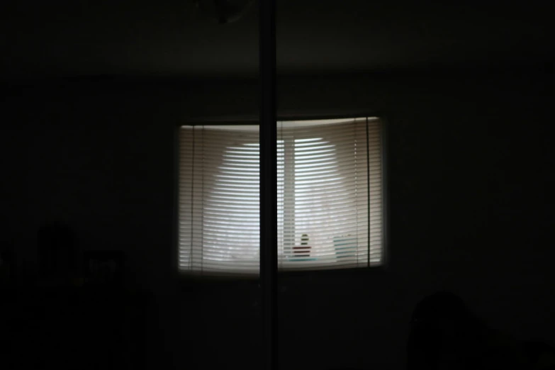 a dark room with an open window that has blinds in the top