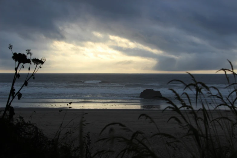 a cloudy ocean with the sun shining on it