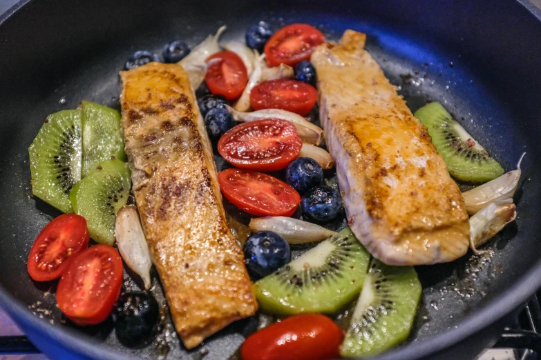 fish and fruit in a pan on a stove top