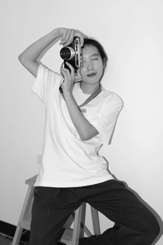 black and white pograph of man sitting on stool with camera