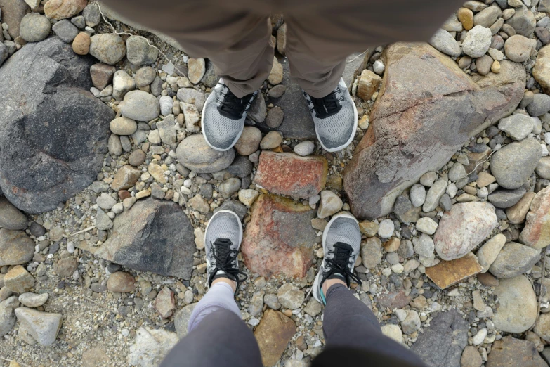 a man with sneakers is standing on rocks looking down