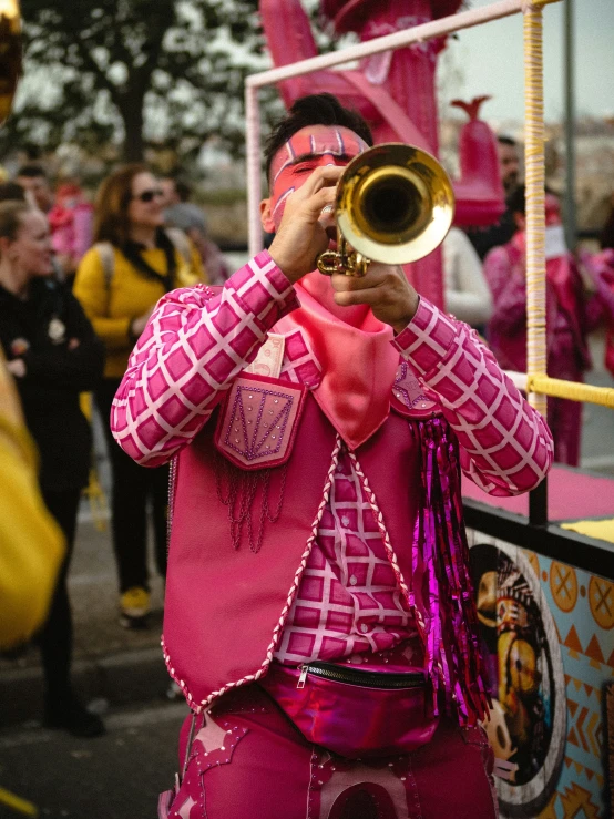 a man with pink makeup playing trumpet