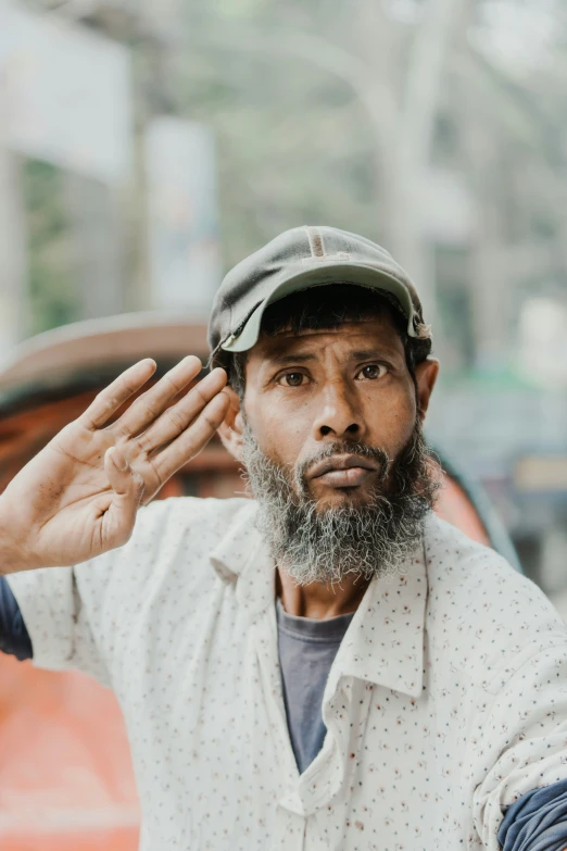 a man wearing a hat and holding his hand up