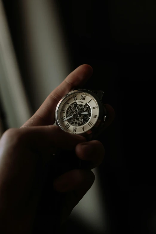 a hand holding an alarm clock in the dark